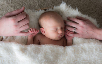 Bébé qui dort dans panière avec mains des parents Emilie Champeyroux Photographies Auvergne Riom Aigueperse
