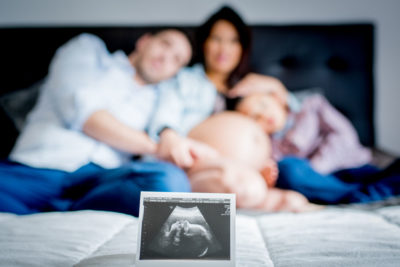 Famille sur le lit avec échographie grossesse Emilie Champeyroux Photographies Auvergne Riom Aigueperse